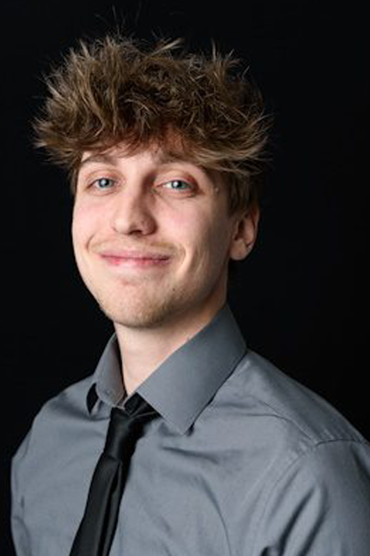 A man with a messy hair style wearing a shirt and tie.